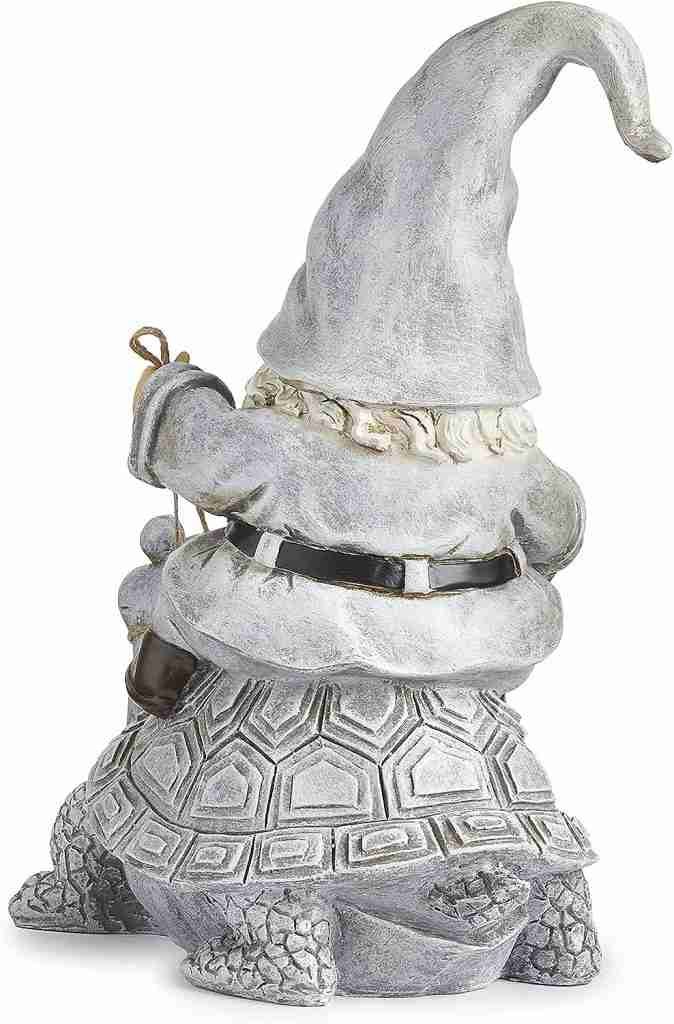 Statue of a gnome wearing a tall hat, sitting on a large turtle, facing backward.