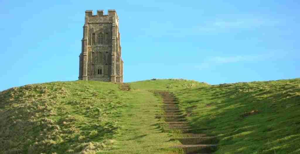 Stone tower atop a grassy hill with a staircase leading up.