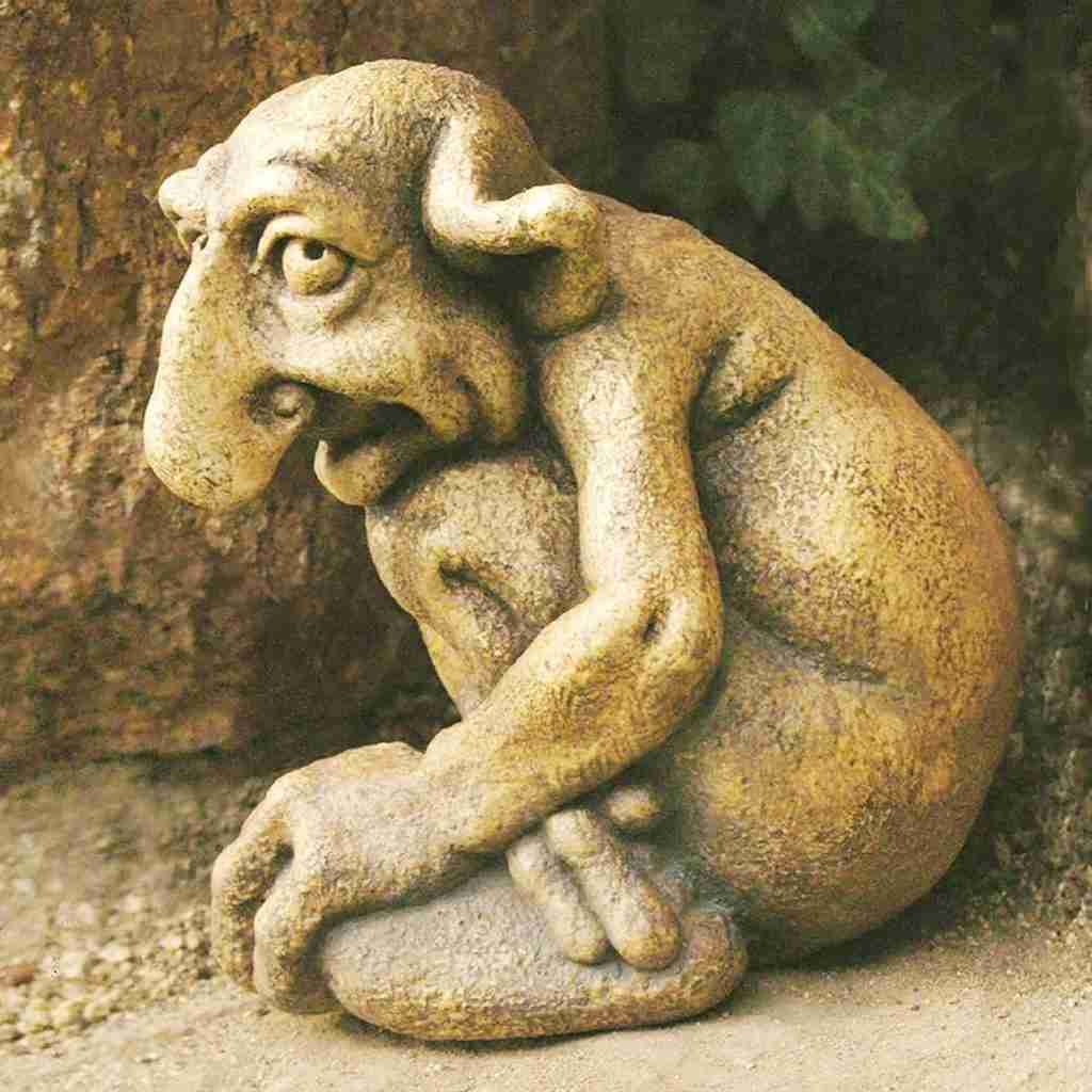 Stone sculpture of a mythical creature with a large nose and huddled posture.