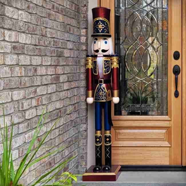 A tall nutcracker statue in a traditional soldier uniform stands next to a glass-paneled wooden door outside a house with brick walls.