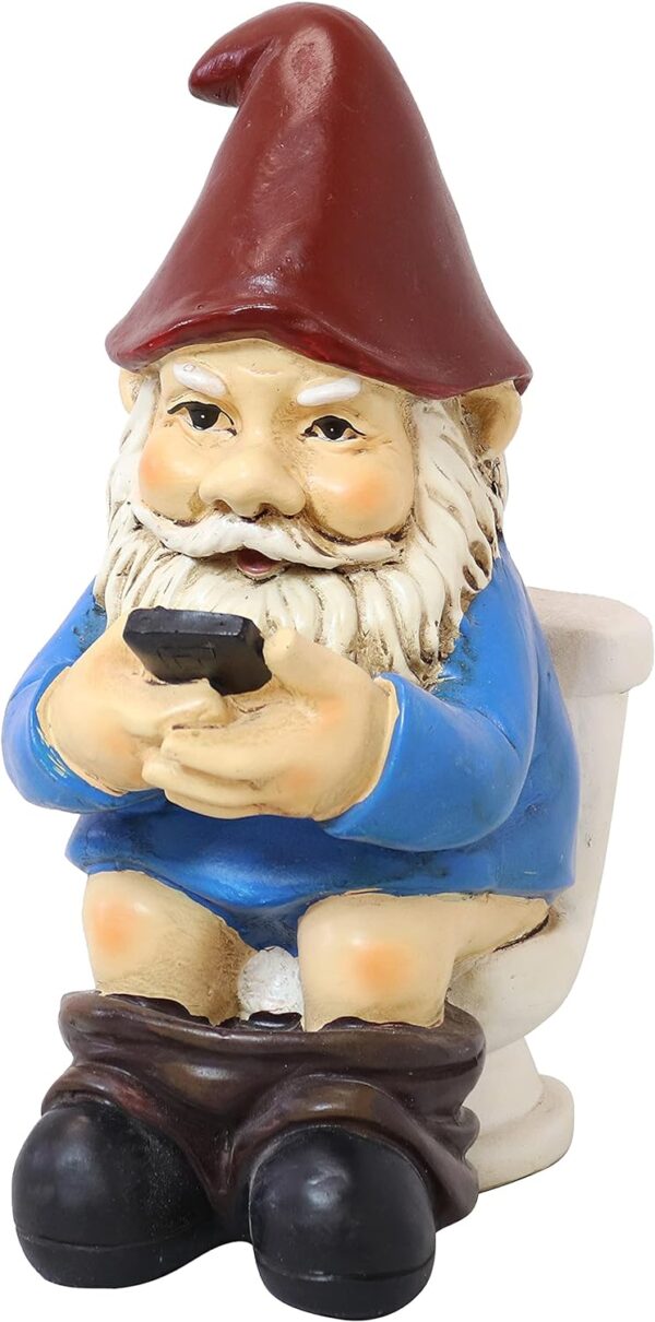 Garden gnome figurine wearing a red hat and blue shirt, sitting on a toilet and holding a smartphone.