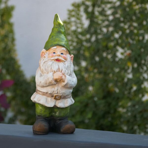 A garden gnome statue with a green hat, white beard, and green pants standing on a surface, with greenery in the background.